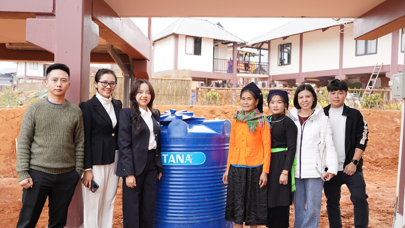 A group of women standing next to a blue barrel  Description automatically generated