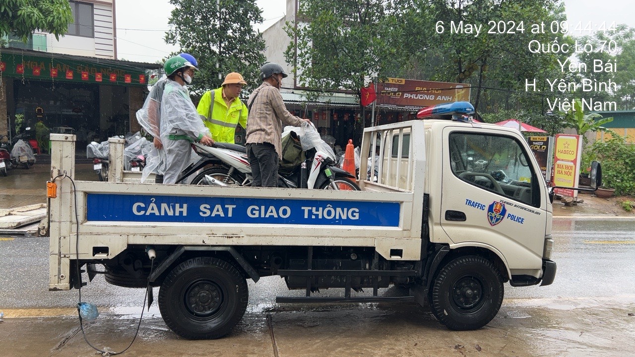 Cảnh sát giao thông Yên Bái đội mưa giúp người dân qua vùng ngập nước an toàn- Ảnh 1.