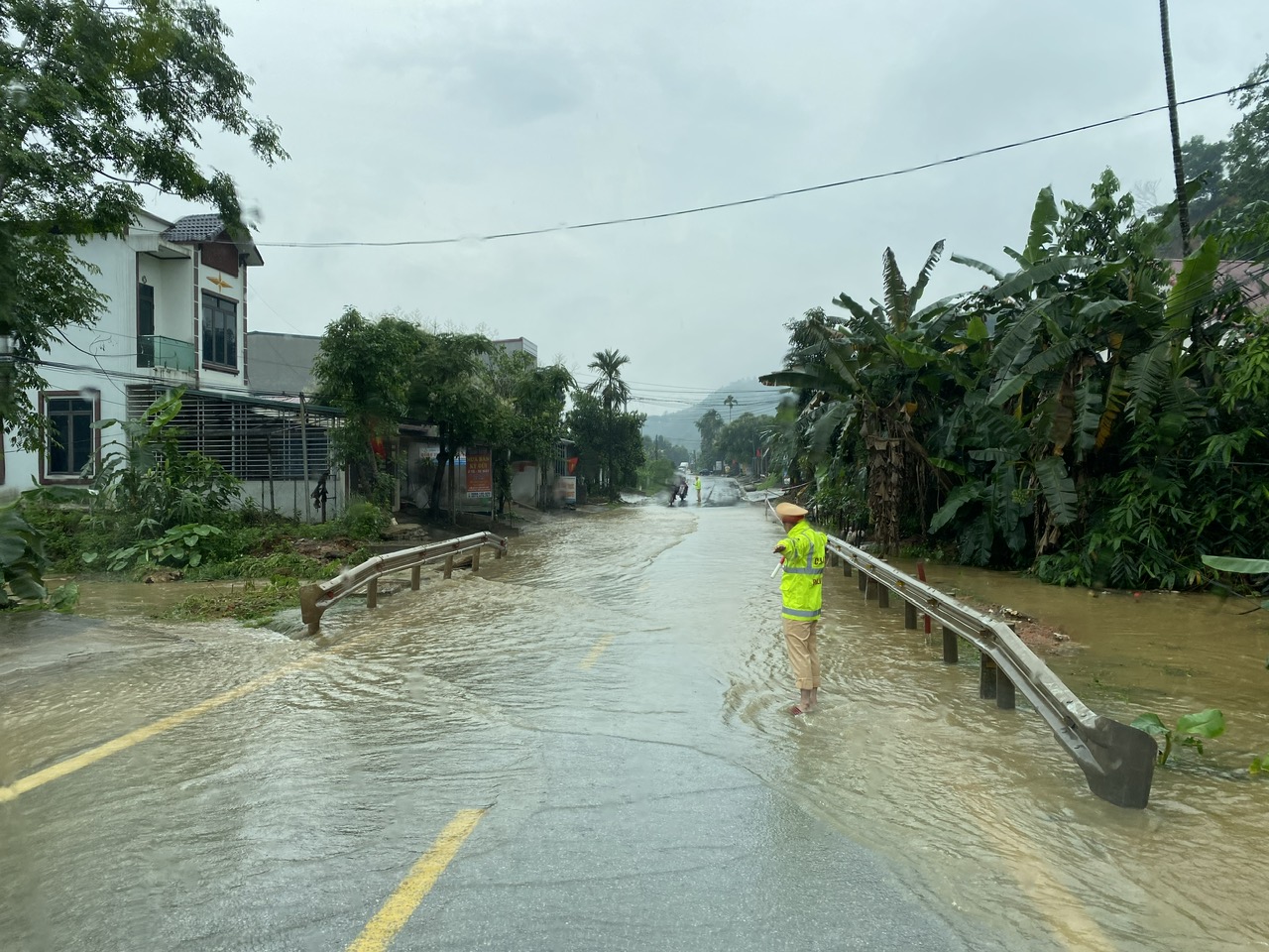 Cảnh sát giao thông Yên Bái đội mưa giúp người dân qua vùng ngập nước an toàn- Ảnh 2.