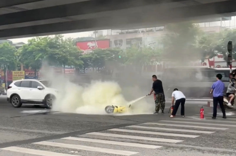 Người dân và lực lượng chức năng dập tắt chiếc xe máy bốc cháy.