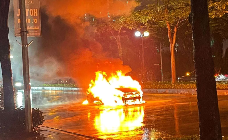 Chiếc ô tô bốc cháy ngùn ngụt dưới trời mưa - Ảnh: Minh Tuệ.