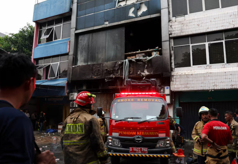 Cháy tòa nhà văn phòng ở Jakarta, Indonesia, 22 người thiệt mạng- Ảnh 1. A firemen standing next to a fire truck AI-generated content may be incorrect.