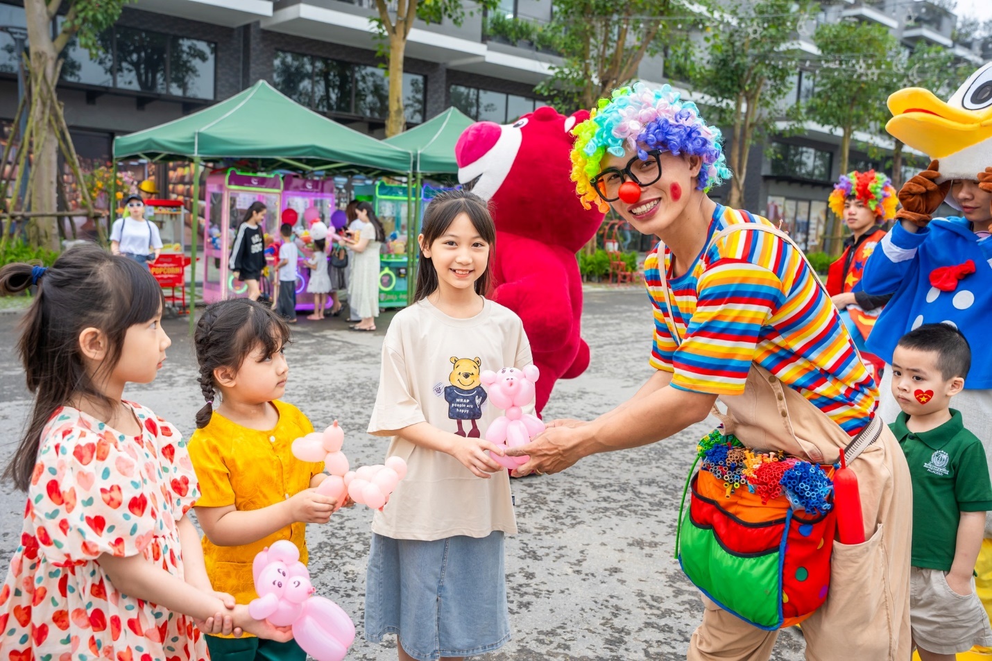 Giải phóng đôi chân, trải nghiệm mùa hè rực rỡ tại “Lễ hội mùa hè Eco Central Park 2025”- Ảnh 3. A clown giving a group of kids a balloon animal Description automatically generated