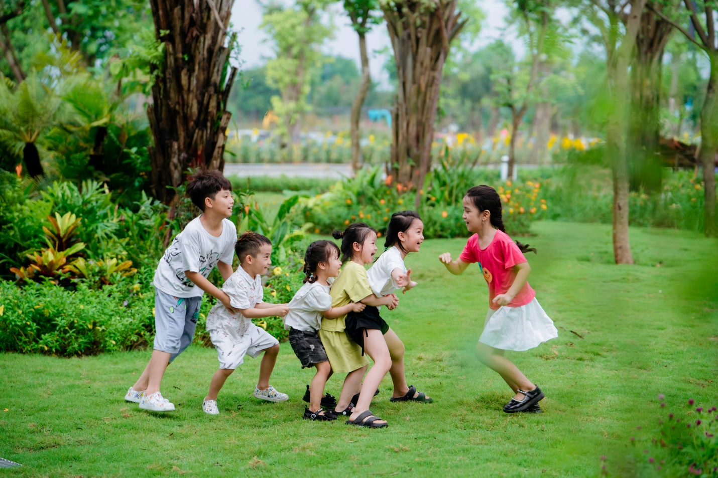 Giải phóng đôi chân, trải nghiệm mùa hè rực rỡ tại “Lễ hội mùa hè Eco Central Park 2025”- Ảnh 9. A group of children playing in the grass Description automatically generated