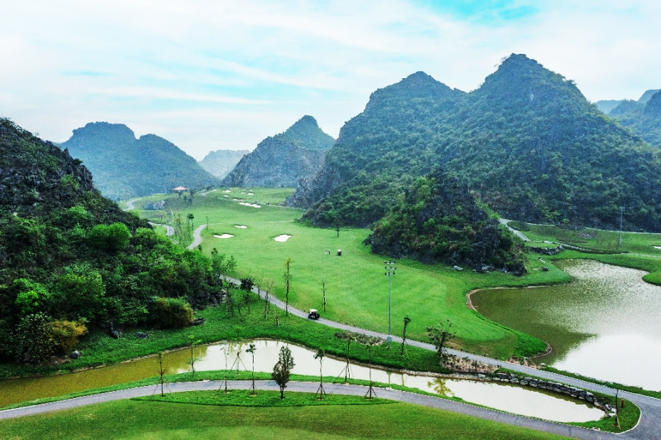 Legend Valley Hà Nam: Giao điểm giữa thiên đường nghỉ dưỡng và gôn- Ảnh 1. A green field with water and mountains AI-generated content may be incorrect.