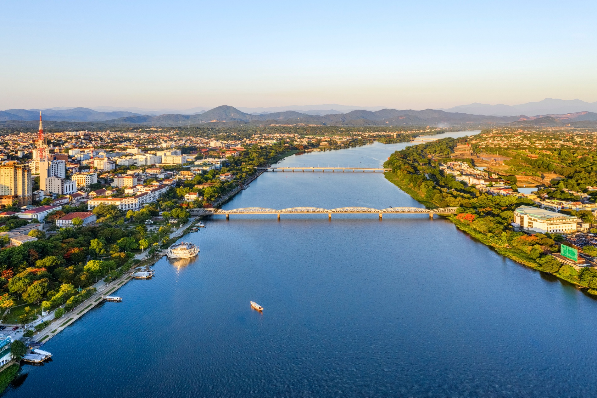 A river with a bridge and a city  Description automatically generated