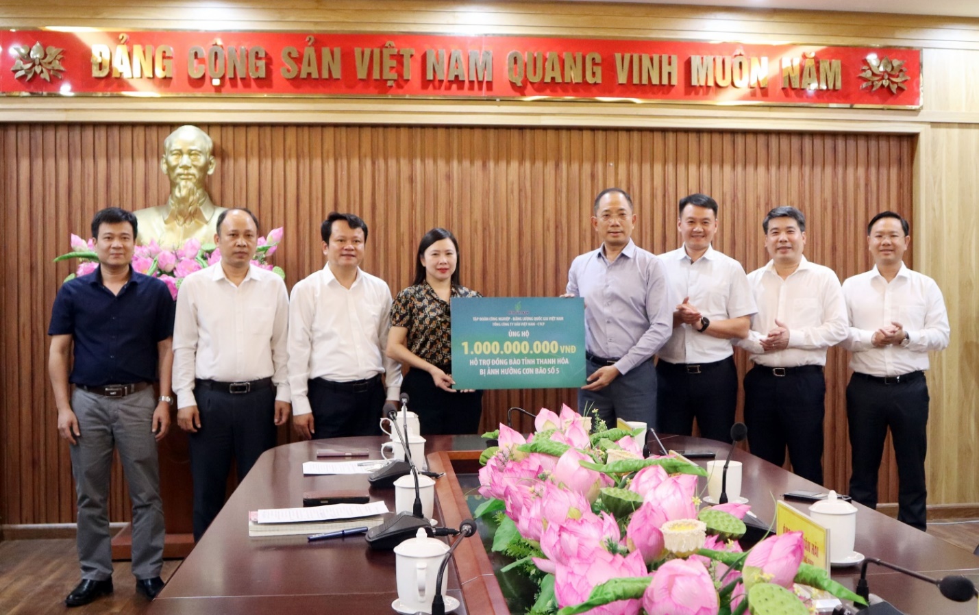 Petrovietnam chung tay hỗ trợ khắc phục hậu quả bão số 5- Ảnh 3. A group of people standing in front of a table with flowers AI-generated content may be incorrect.