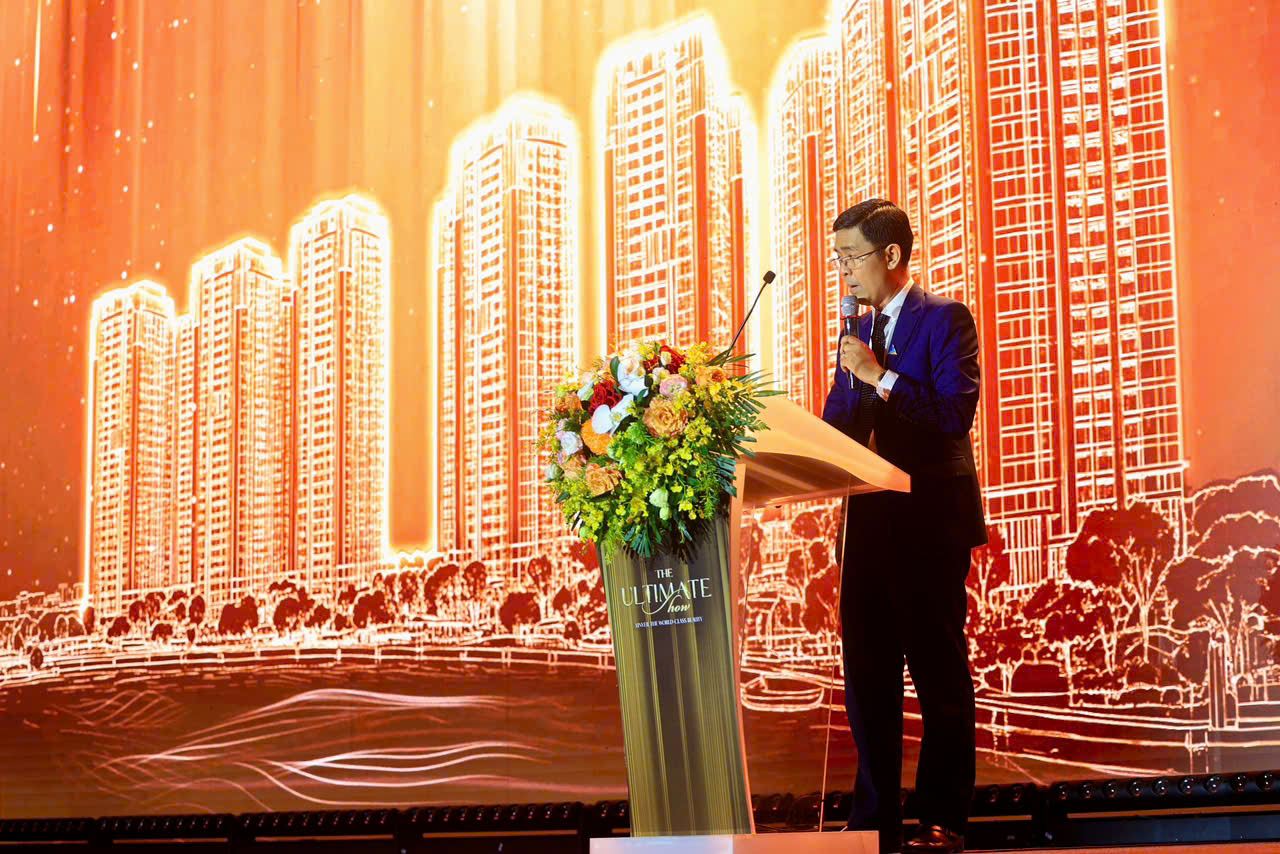 A person standing at a podium with a microphone and flowers  Description automatically generated