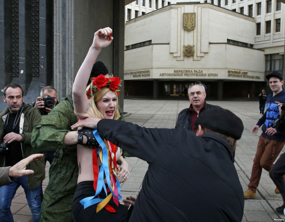 Các thành viên đơn vị tự vệ Crimea ngăn chặn một nhà hoạt động của nhóm nữ quyền Femen biểu tình gần tòa nhà quốc hội ở Simferopol, ngày 6-3-2014.