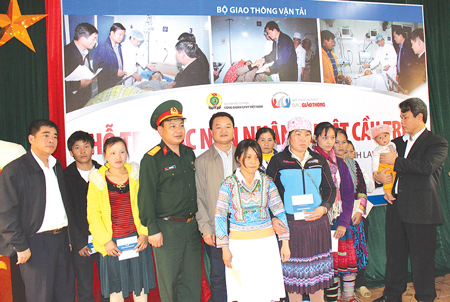 Ông Đỗ Nga Việt - Chủ tịch công đoàn GTVT VN (người bế cháu nhỏ) và ông Nguyễn Bá Kiên - Tổng Biên tập Báo Giao thông (người thứ 5 từ trái qua) trao quà từ thiện cho các nạn nhân