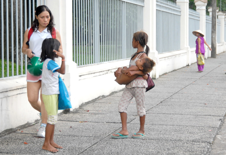 Trẻ em ăn xin đang chèo kéo một người đi đường tại TP HCM 