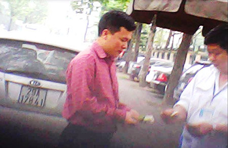 Nhân viên trông xe thu tiền “tươi” phí trông xe của PV Báo Giao thông (hình cắt từ clip)