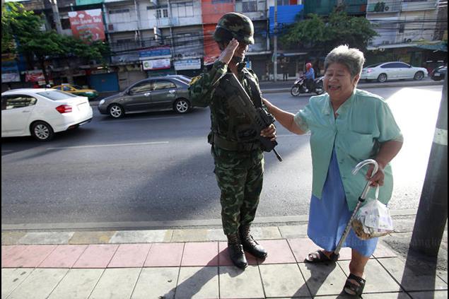 Một người lớn tuổi tại Thái Lan tươi cười chào binh lính đang làm nhiệm vụ