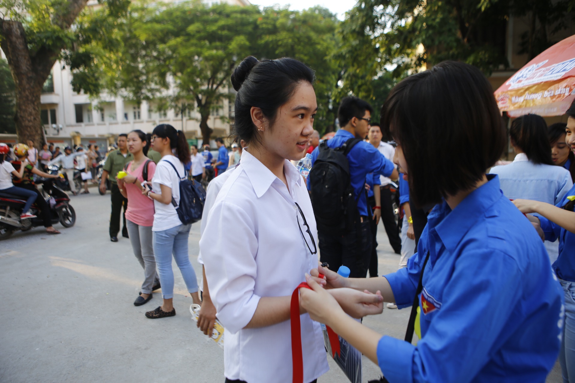 Một sinh viên tình nguyện đang thắt chiếc dây đỏ may mắn động viên tinh thần các sĩ tử trước khi vào trường thi.