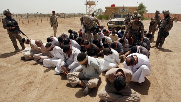 Binh lính Iraq bên cạnh những nghi phạm khủng bố al-Qaeda bị còng tay, bịt mắt tại một căn cứ quân sự của Iraq ngày 20/7/2012