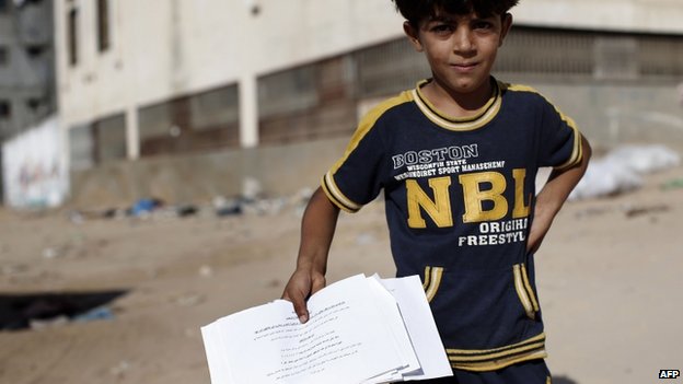 Một em nhỏ người Palestin cầm trong tay tờ rơi cảnh báo đi sơ tán của chính phủ Israel
