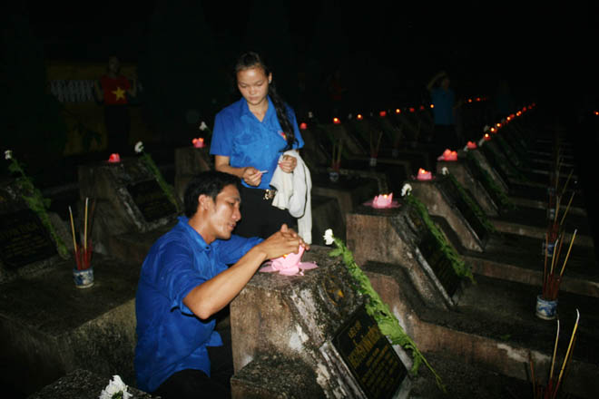 Các đoàn viên, thanh niên tình nguyện chăm chút từng cây nến, cành hoa trên mộ các liệt sỹ (ẢnhL Lao Động)