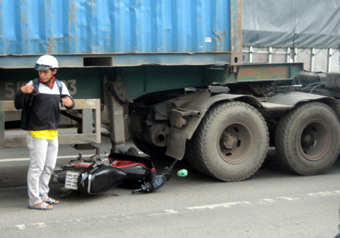 Chiếc xe máy nằm gọn dưới gầm xe container nhưng nạn nhân đã may mắn thoát nạn.
