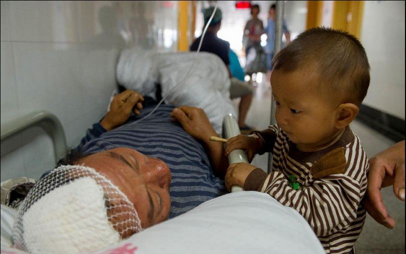 Em nhỏ bên giường bệnh của người bố bị thương do thảm họa động đất tại tỉnh Vân Nam, Trung Quốc