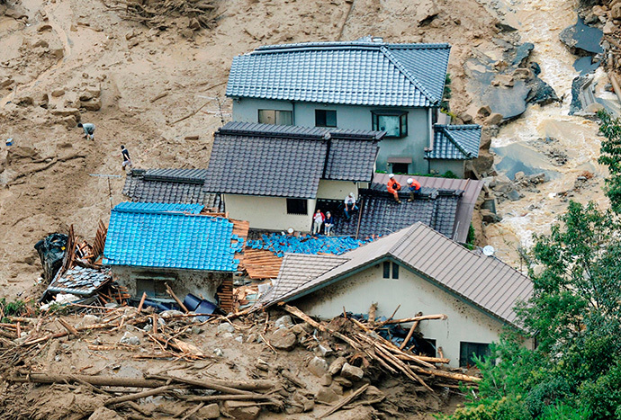 Người dân đứng trên các nóc nhà bị sập đang chờ được cứu hộ. Ảnh: Reuters/Kyodo