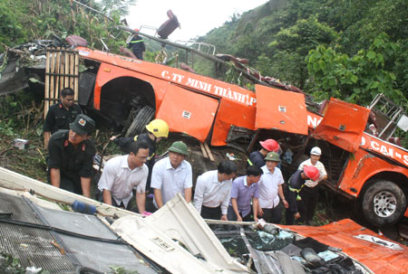 Bộ trưởng Đinh La Thăng (hàng trước, thứ ba từ trái qua) cùng lực lượng chức năng nâng nóc chiếc xe gặp nạn để kiểm tra liệu còn nạn nhân nào sót lại