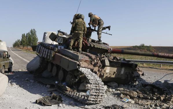 Binh lính Ukraine đang kiểm tra một chiếc xe tăng bị phá hủy tại ngoại ô thành phố cảng Mariupol