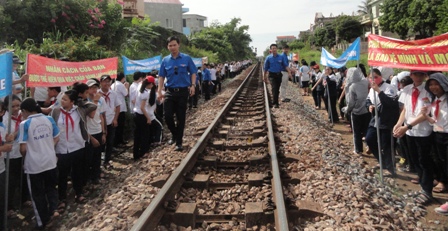 Đoàn thanh niên phát tờ rơi những quy định của pháp luật về hành lang an toàn giao thông đường sắt cho các em học sinh.