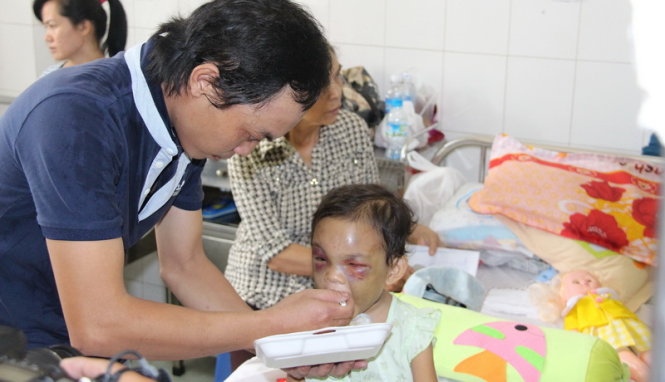 Anh Trần Văn Tố bế và chăm sóc bé Kim Ngân tại bệnh viện (Ảnh: Tuổi trẻ)