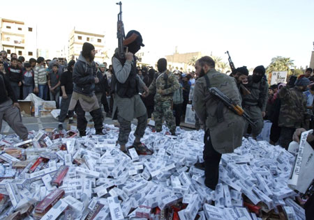 Chiến binh IS đứng trên đống hộp thuốc lá cướp được tại TP Raqqa