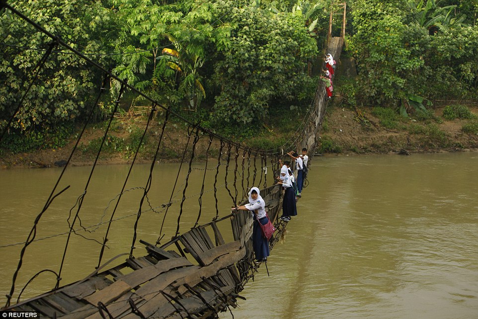 Học sinh tại Indonesia bám các thanh sắt trên cây cầu bị gãy vượt sông Ciherang, gần làng Lebak Regency.