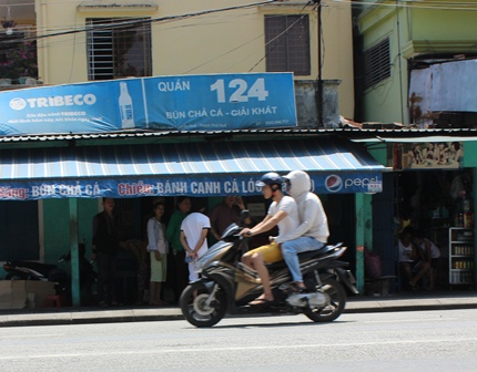 Đối tượng Nguyễn Hữu Quang mặc áo chống nắng, được đèo ra khỏi hiện trường (Ảnh: Dân Trí)