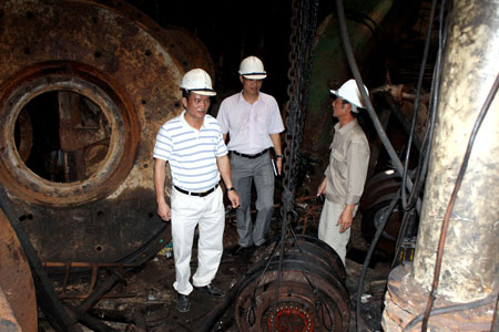Ông Tuấn (ngoài cùng bên trái) trong lòng con tàu Trần Hưng Đạo với ngổn ngang máy móc bị rụng rời, hoen gỉ