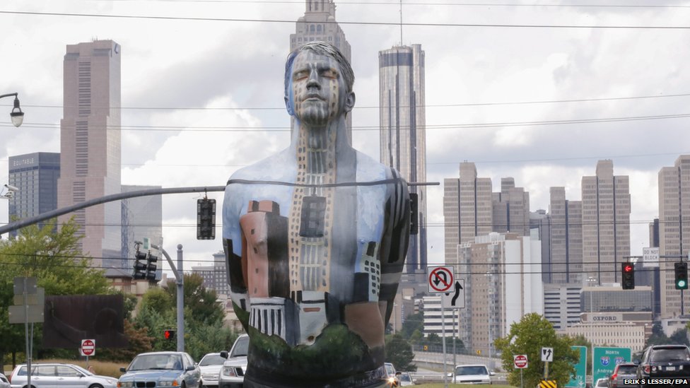 First-time model Jon Leonardo blends into the skyline of Atlanta after being covered in camouflaged body paint by Italian artist Johannes Stoetter. 