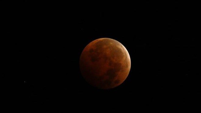 Đĩa mặt trăng đang chuyển dần từ màu cam sang màu đỏ trong bức ảnh do người yêu thiên văn chụp tại thành phố Erie, bang Pennsylvania, Mỹ. Ảnh: AP