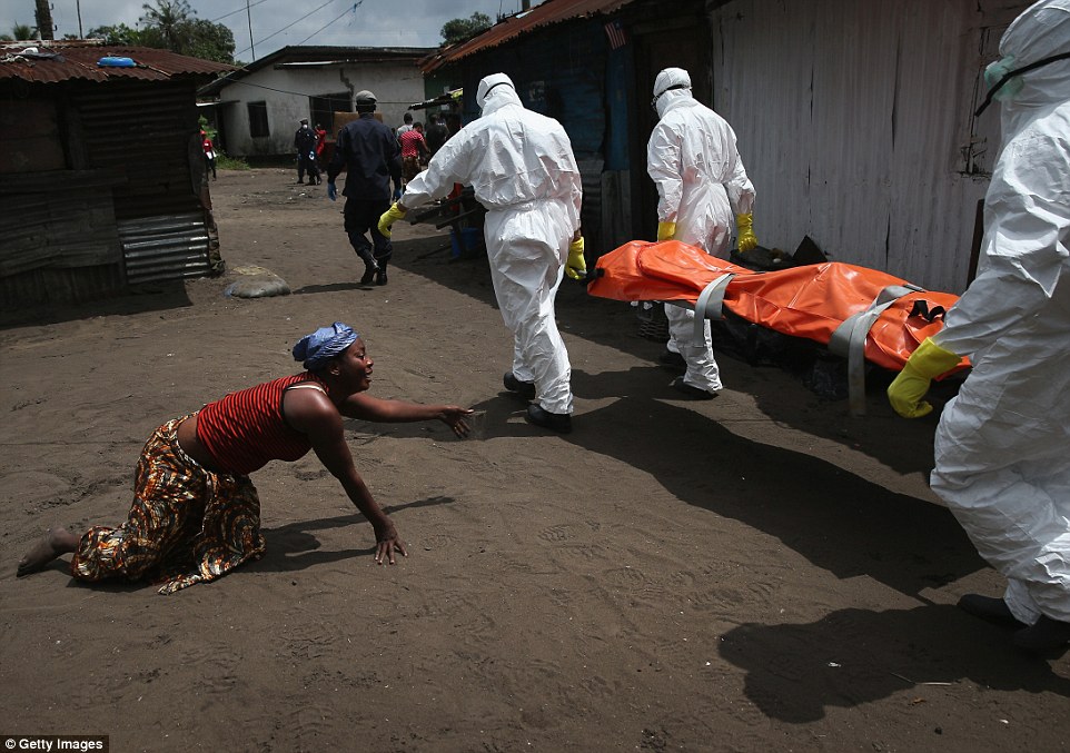 Một người phụ nữ khóc ngất, bò tới thi thể người chị vừa qua đời vì Ebola trong khi đội cứu hộ đang đưa thi thể đi chôn