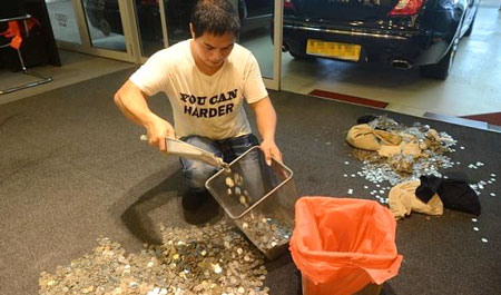 Nhân viên cửa hàng đang dọn số tiền xu trị giá 19 nghìn USD vào túi nilon bóng để trả lại ông Lester Ong Boon Lin