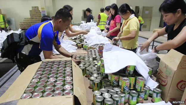 Các đội tình nguyện đang chuẩn bị thực phẩm cứu trợ bên trong một nhà kho tại Manila