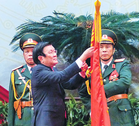 Chủ tịch nước Trương Tấn Sang gắn Huân chương Sao Vàng lên lá cờ truyền thống của QĐND Việt Nam Ảnh: TTO
