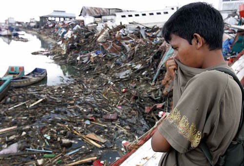 Người đàn ông này đang tìm kiếm người thân trong những mảnh vỡ và thi thể trôi nổi trên sông Aceh River ở Aceh, Indonesia