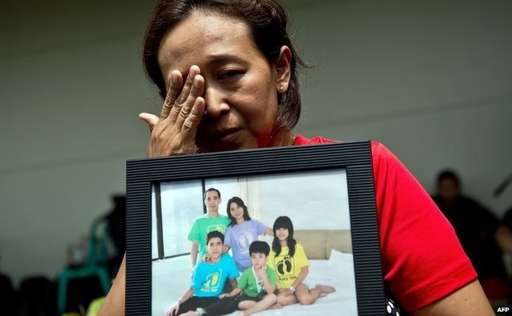 Một thân nhân cầm bức ảnh của những gia đình người thân có mặt trên chuyến bay mất tích QZ8501