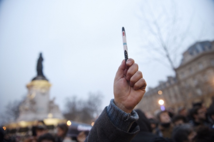 Người biểu tình giơ cao bút và báo Charlie Hebdo để tưởng nhớ những phóng viên đã thiệt mạng