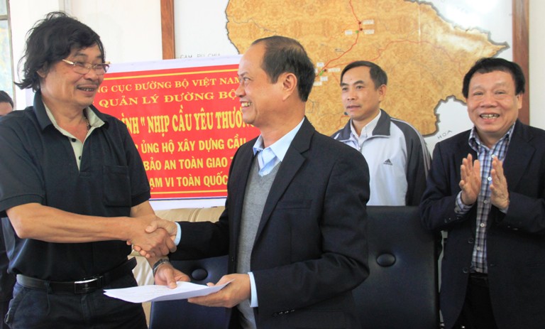Ông Phạm Ngọc Thành, Giám đốc Công ty CP Quản lý và sửa chữa đường bộ Đắk Lắk trao biên bản khuyên góp 100 triệu đồng, ủng hộ xây cầu dân sinh.
