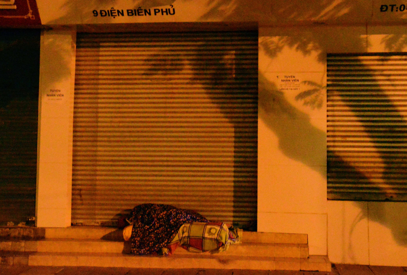 Một người vô gia cư nằm ngủ trên bậc thềm đường Đi