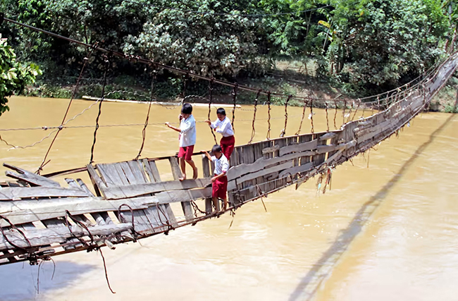 Cây cầu ván, Indonesia: Hãy tưởng tượng bạn sẽ đi như thế nào trên cây cầu treo lơ lửng này ở Indonesia? Vậy mà những đứa trẻ này vẫn hằng ngày đến trường băng qua cây cầu đáng sợ này.