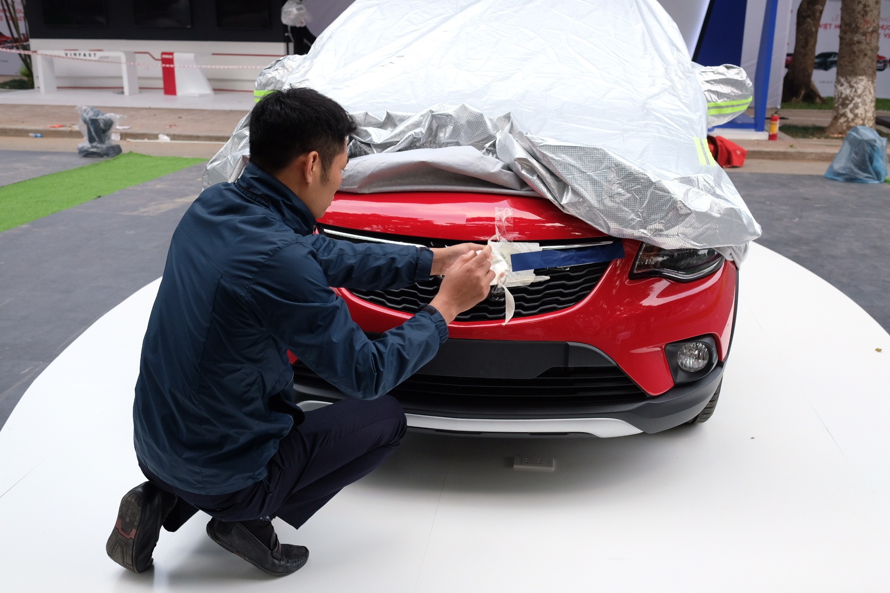 Một nhân viên của hãng đang tháo bỏ lớp bảo vệ logo VinFast phía đầu xe trên chiếc Fadil