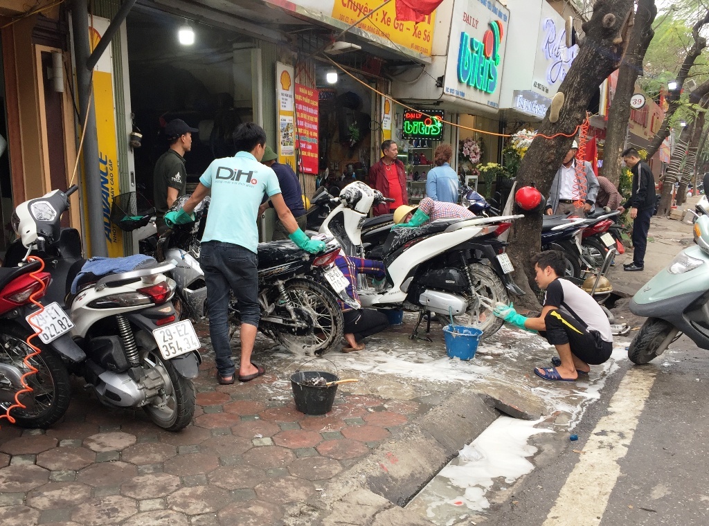 Điểm sửa chữa, bảo dưỡng xe máy trên đường Thái Thịnh xe xếp kín vỉa hè. Ngày thường xe máy rửa xe máy chỉ 20.000đ, ngày Tết 50.000đ/xe.