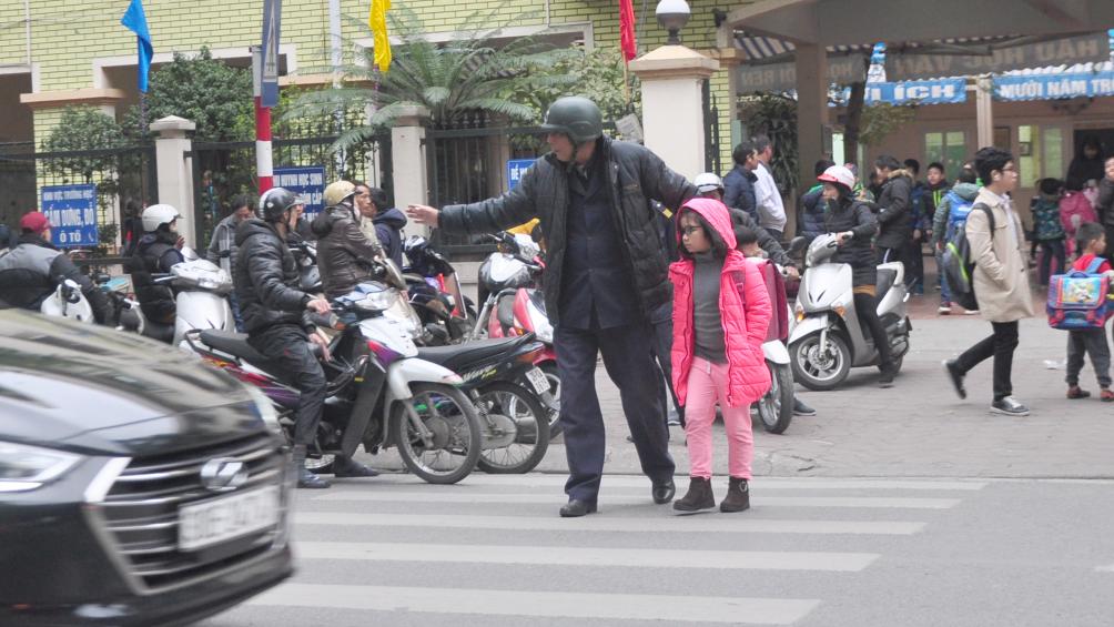 Trật tự phường Điện Biên, Ba Đình tận tình dẫn các em học sinh trường Phan Chu Trinh (nằm trên đường Nguyễn Thái Học) sang đường an toàn.