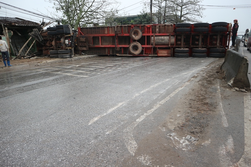 Chiếc xe container sau khi tông vào 2 xe ô tô thì lao vào dải phân cách húc gãy biển báo rồi lao vào nhà dân lật nghiêng