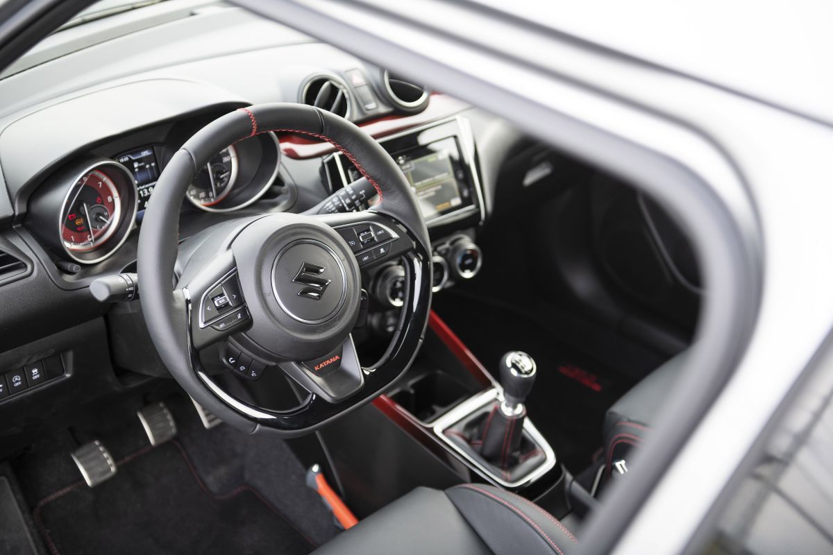 Màu đỏ cũng là điểm nhấn trong khoang nội thất của Swift Sport Katana khi được sử dụng cho các đường chỉ khâu trên bảng điều khiển trung tâm, ghế ngồi cho tới thảm sàn. Biểu tượng Katana được thêu ở nhiều vị trí như bên hông ghế, vô lăng thể thao, thảm sàn