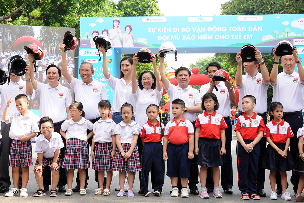 Các đại biểu cùng giơ cao những chiếc mũ bảo hiểm do Honda tài trợ với thông điệp ý nghĩa: "Đội mũ cho con, trọn tình cha mẹ".
